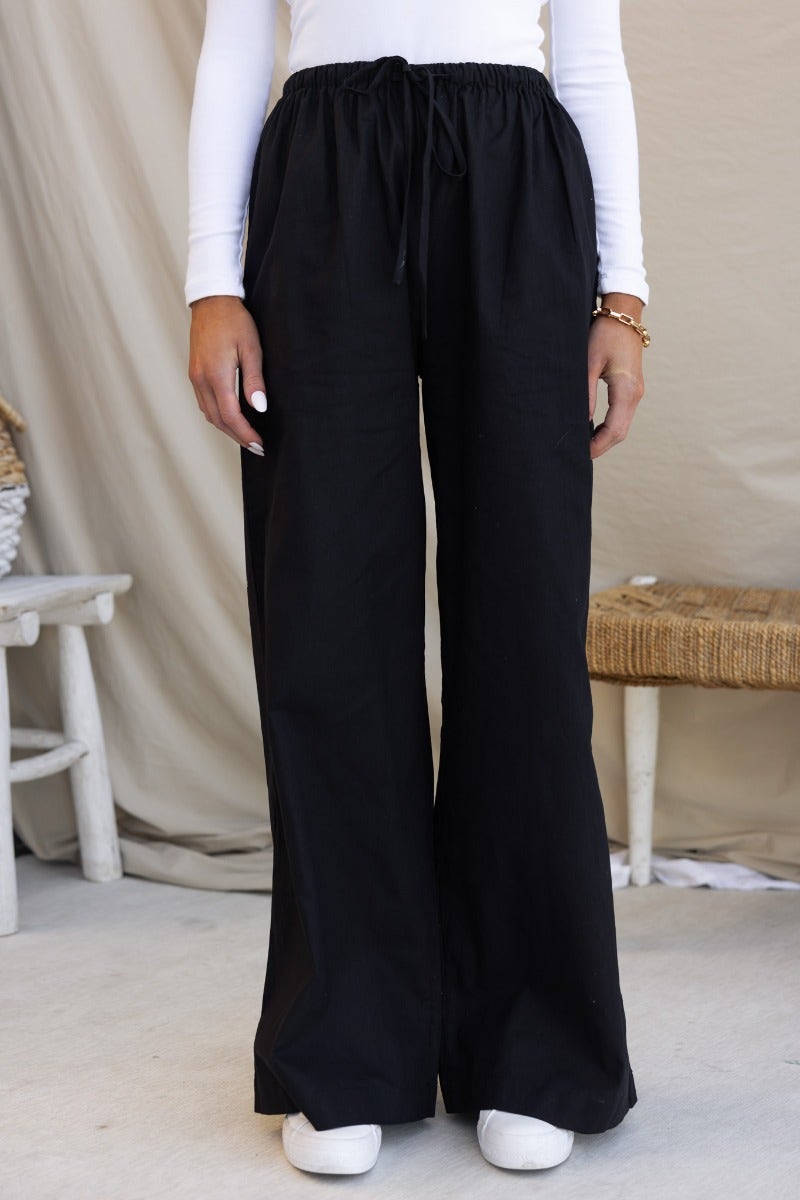 Black cotton Peru pants with elastic waistband and drawstring, wide legs, perfect for a casual look.