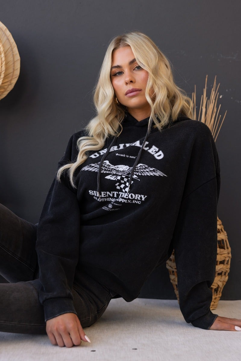 Model wearing Ivar Jumper, a washed black fleece hoodie with 'Unrivaled' print and a drawstring hood.