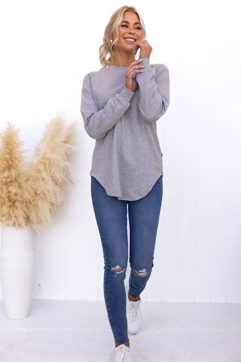 Model wearing Aces Jumper in grey, showcasing round neckline and scallop hemline with jeans, against a white background.