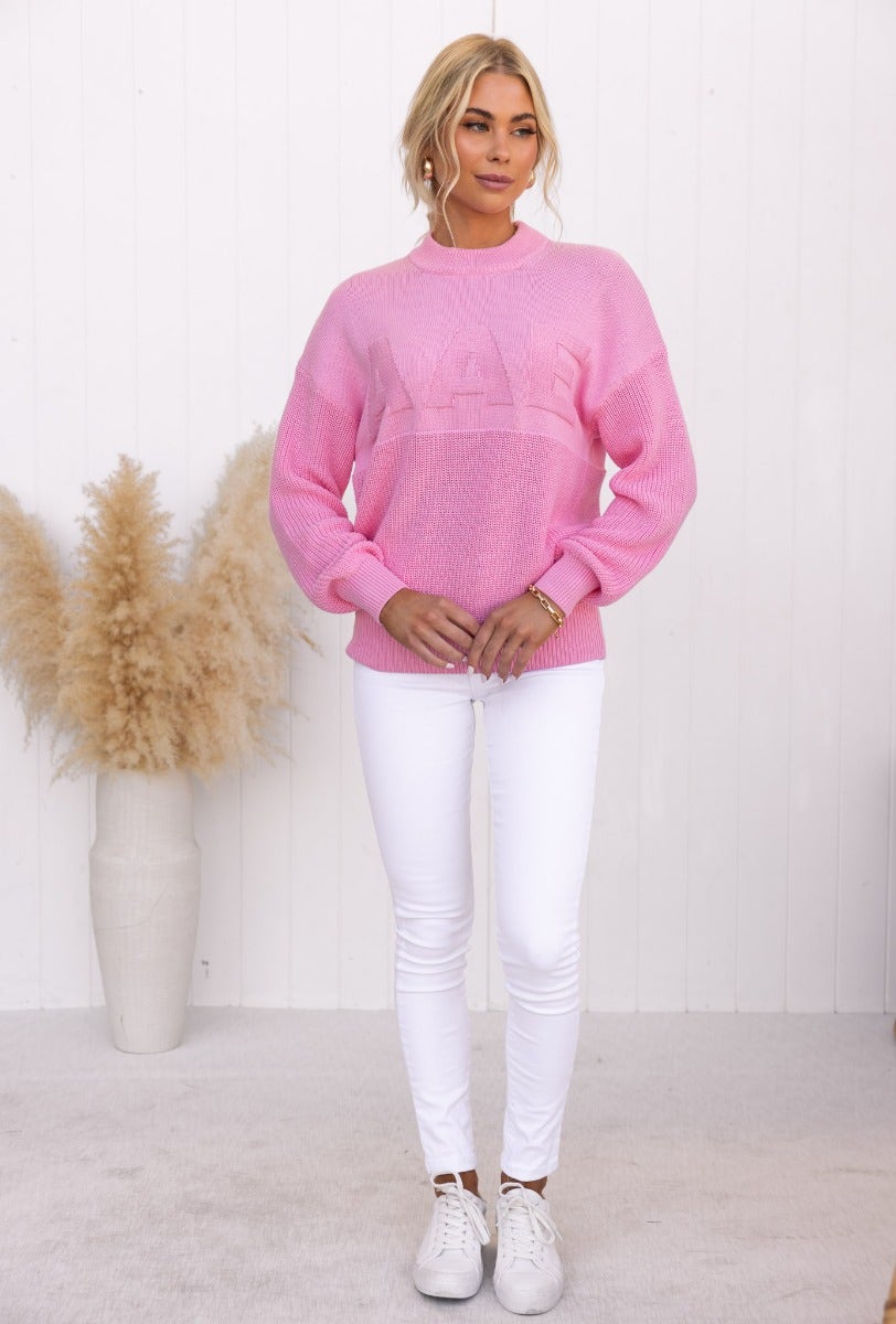 Raymer Jumper in pink, featuring embossed 'AAE', round neckline, paired with white skinny jeans.