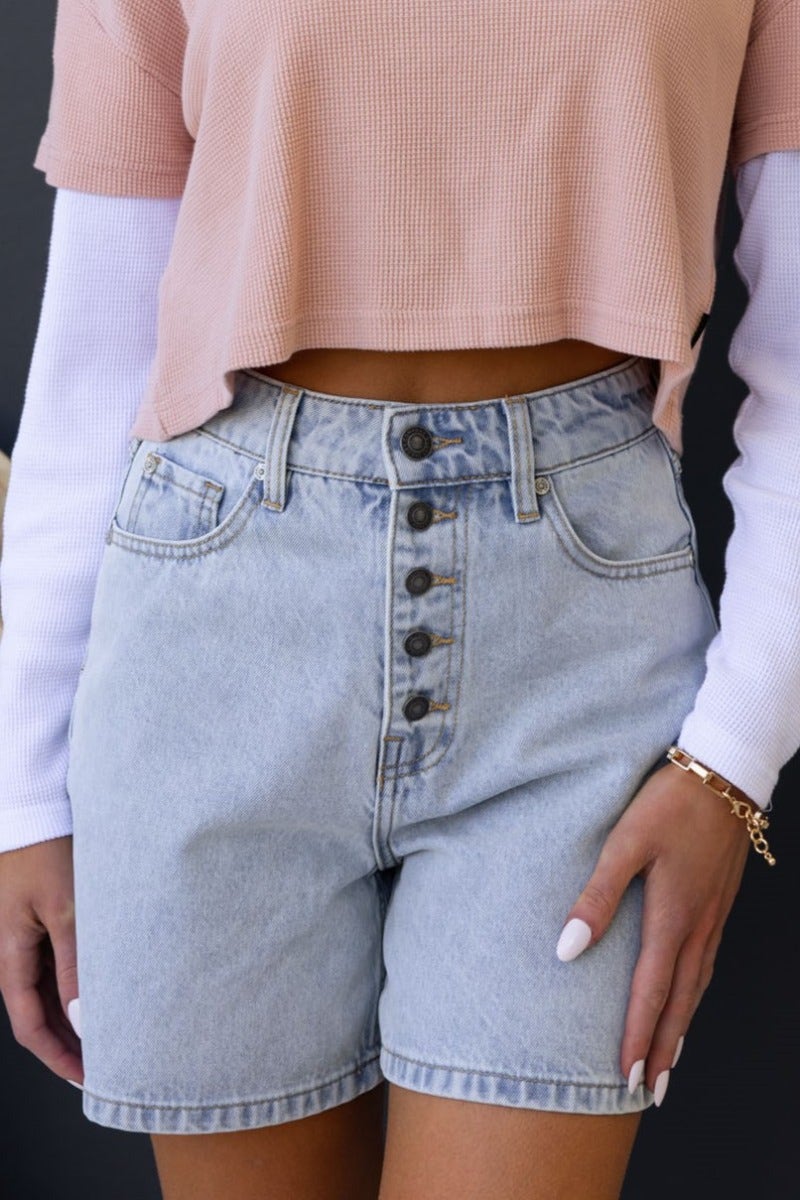 Stazie denim shorts with mid-high waist and button-up front, featuring front and back pockets, styled with a cropped top.
