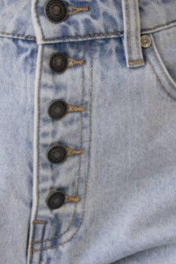 Close-up of Stazie denim shorts showing mid-high waist fit and button-up front detail.