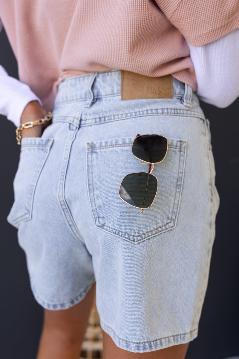 Stazie shorts in light denim with mid-high waist, button-up front, and sunglasses on back pocket.