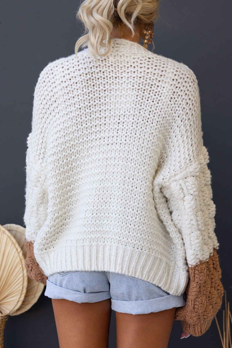 Back view of the Qira Cardigan in a chunky knit design with semi-open weave and oversized sleeves.