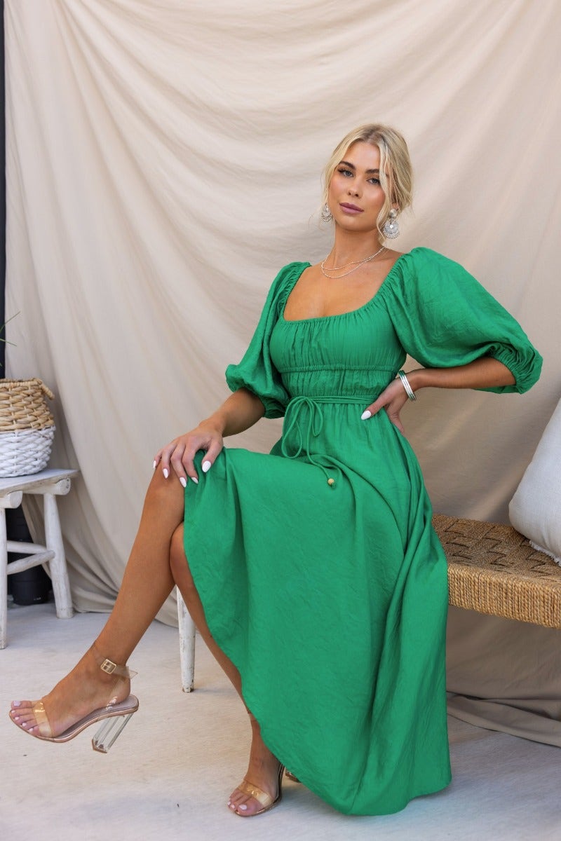 Qove Midi Dress in green, featuring elastic neckline, waistband, and sleeve cuffs, styled with a removable fabric tie.