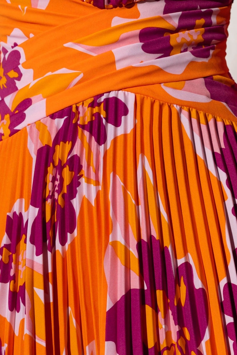 Close-up of Normia Midi Dress showing floral print and pleated fabric in vibrant orange and purple colors.