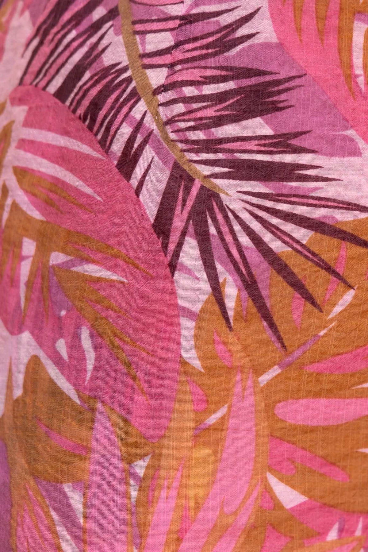Close-up of a multi-colour print fabric featuring pink and orange tropical leaves for Sun Dazed Jumpsuit.