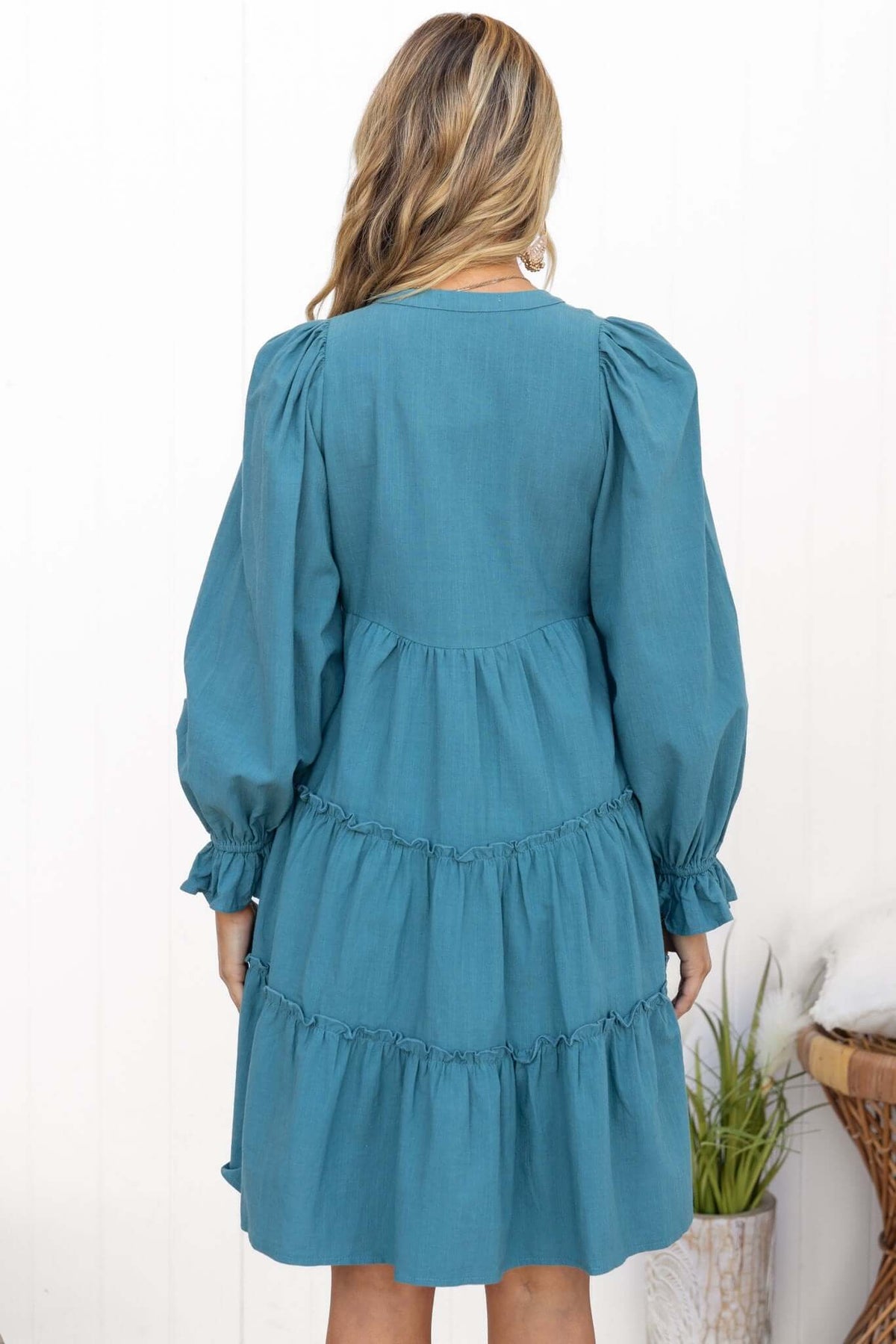 Back view of Boone Dress showcasing its teal color, tiered ruffle design, and puff sleeves.