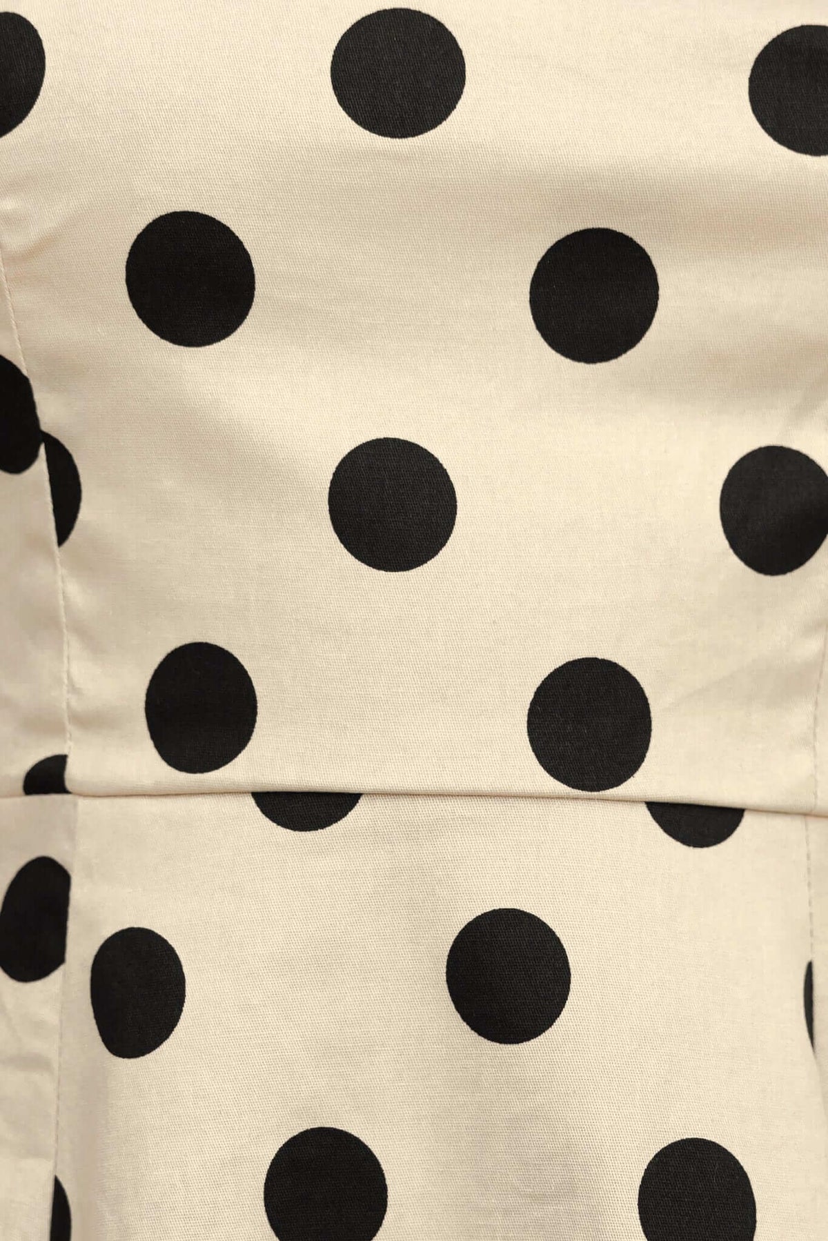 Close-up of beige fabric featuring black polka dots, highlighting the print design of the Orphila Midi Dress.