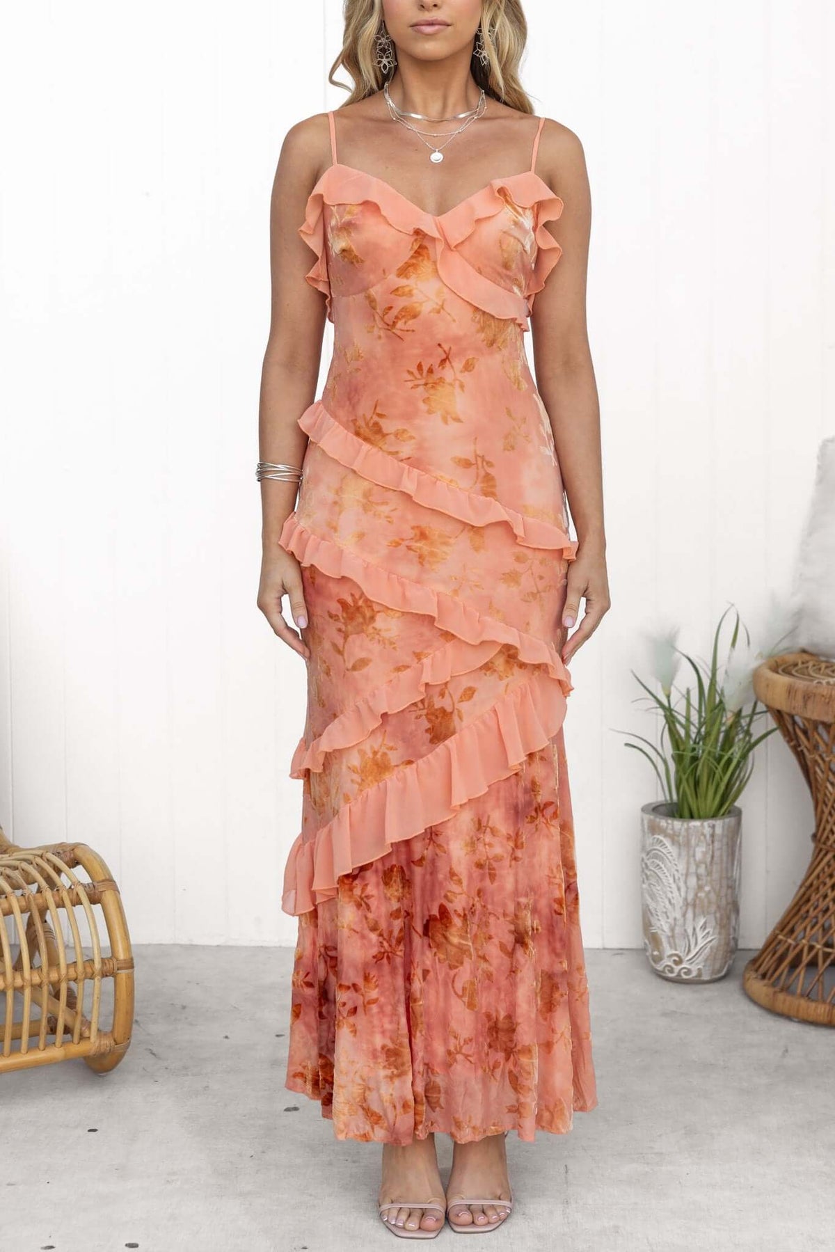 Woman wearing Istelle Maxi Dress with ruffles in peach floral print, adjustable straps, and a flowing design.