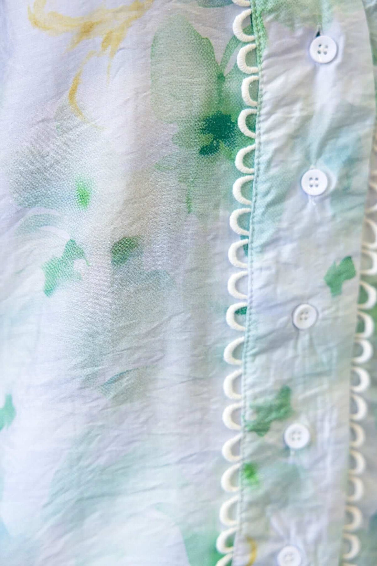 Close-up of Kellee Shirt showing floral pattern, button-up front, and decorative collar trim in soft green tones.