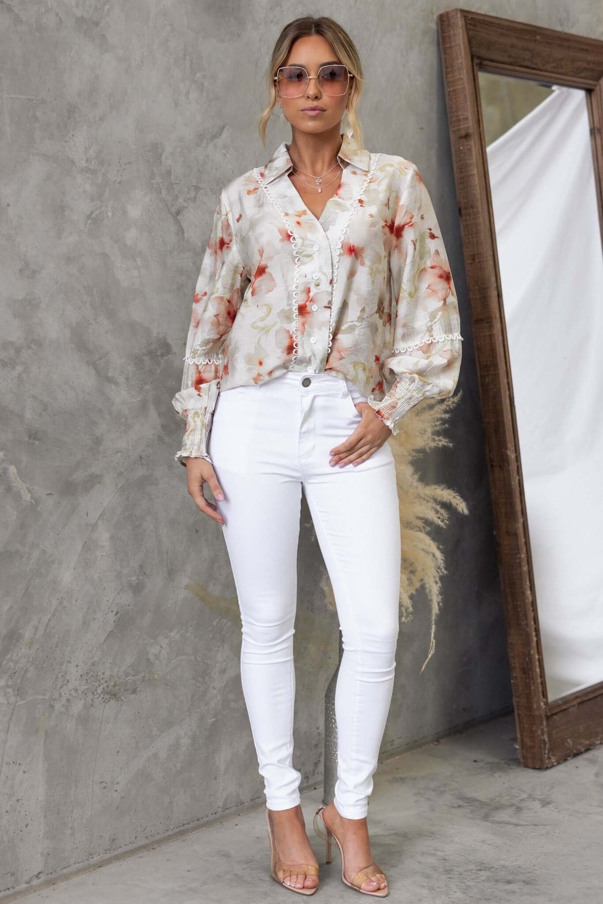 Kellee Shirt in floral design worn with white jeans, showcasing a stylish look with sunglasses.