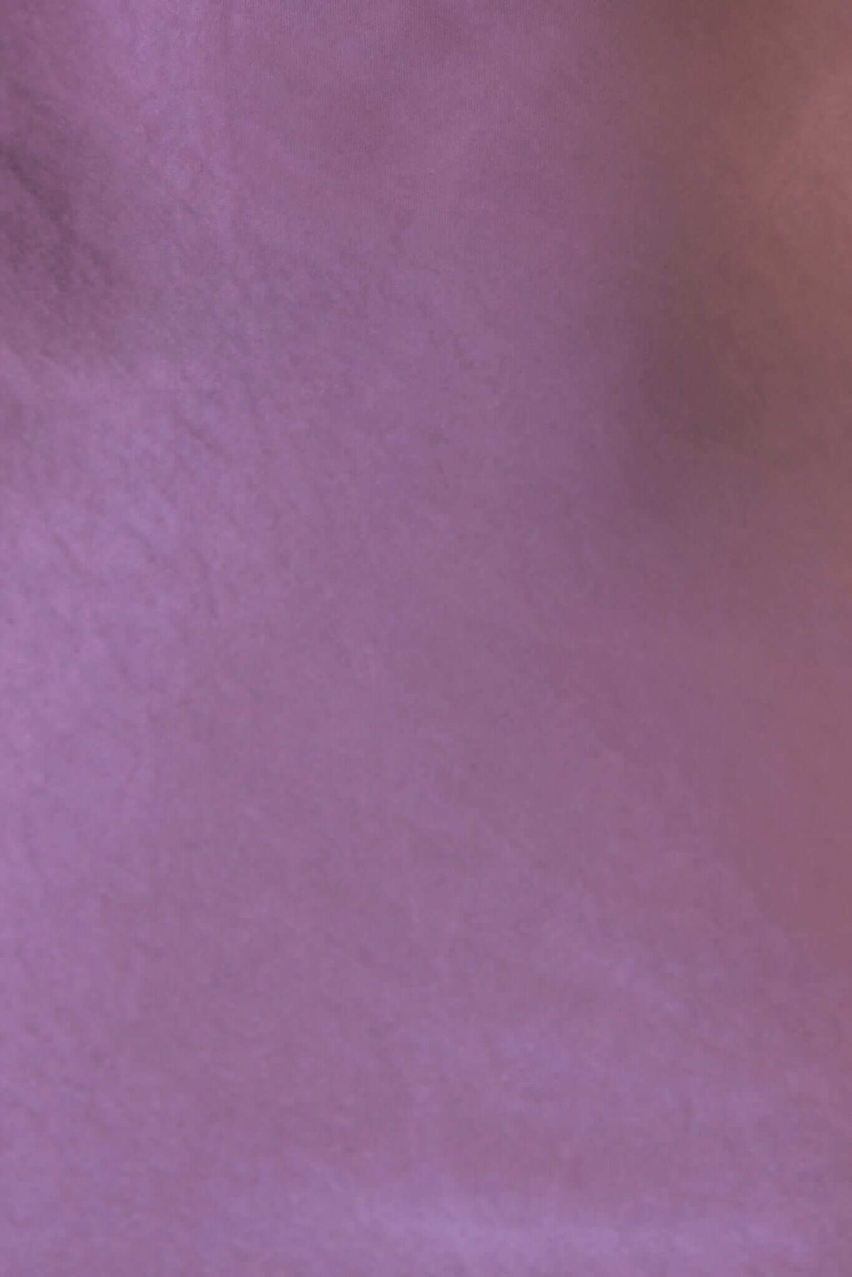 Close-up of smooth purple satin fabric, showcasing its luxurious texture and shimmering appearance.