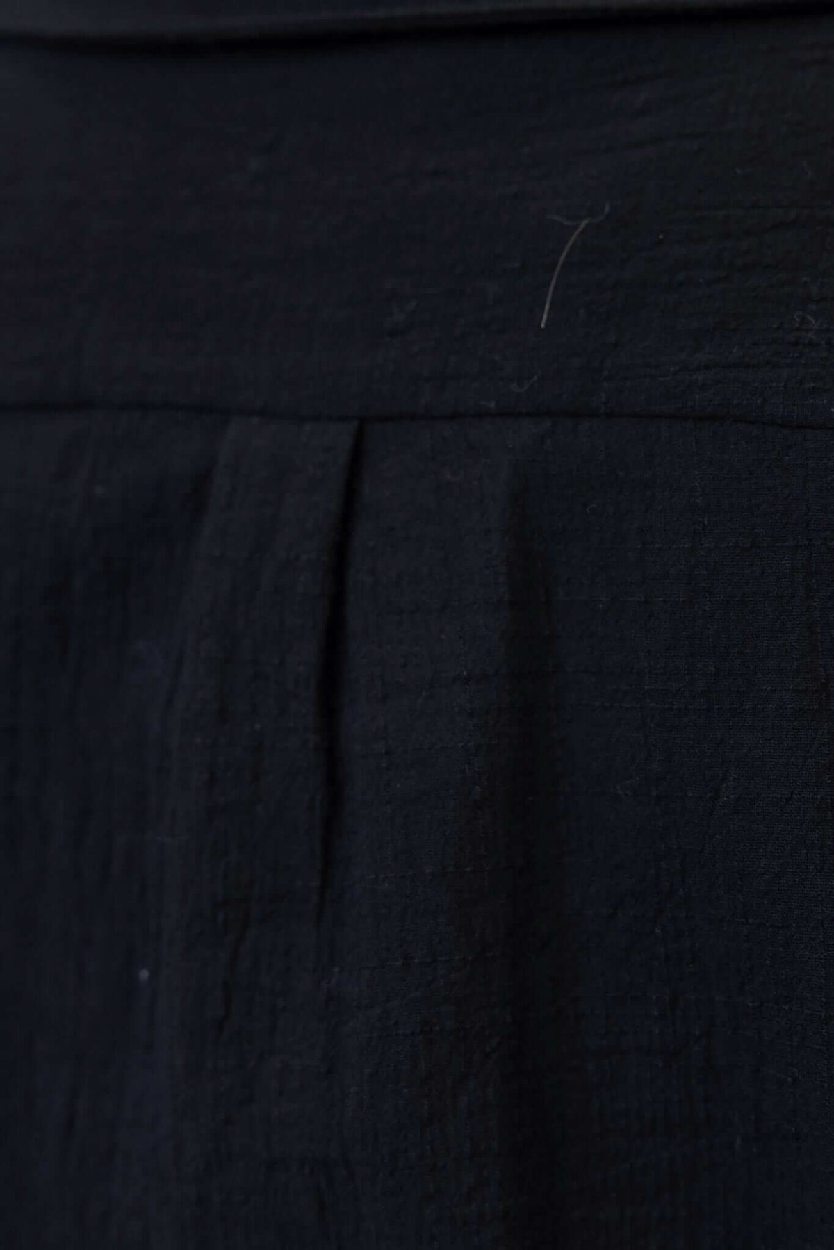 Close-up of the textured fabric of a black Muscat shirt, showcasing its soft cotton appearance and pleated detail.