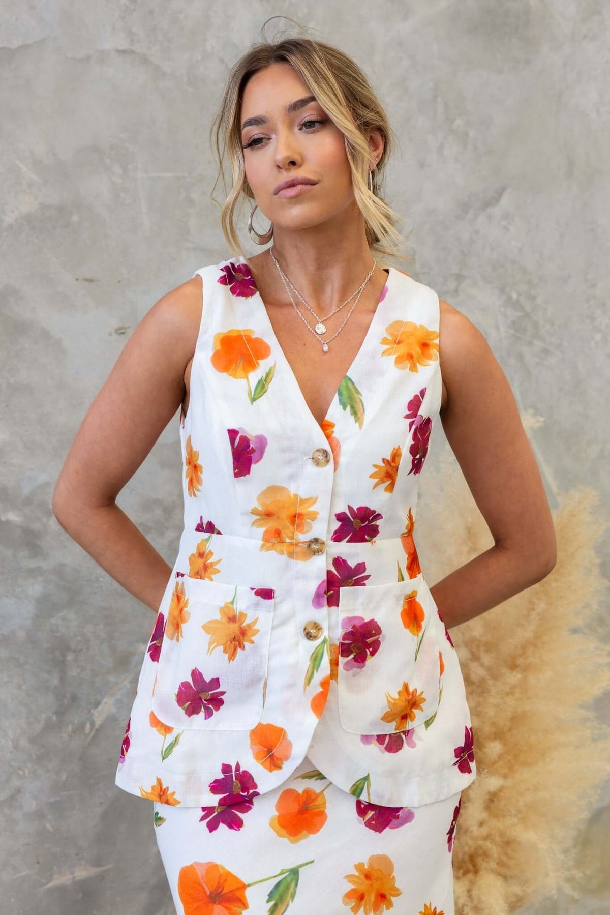 Model wearing the Bexley Top, a floral vest with V-neckline and button-up front, styled with faux pockets.