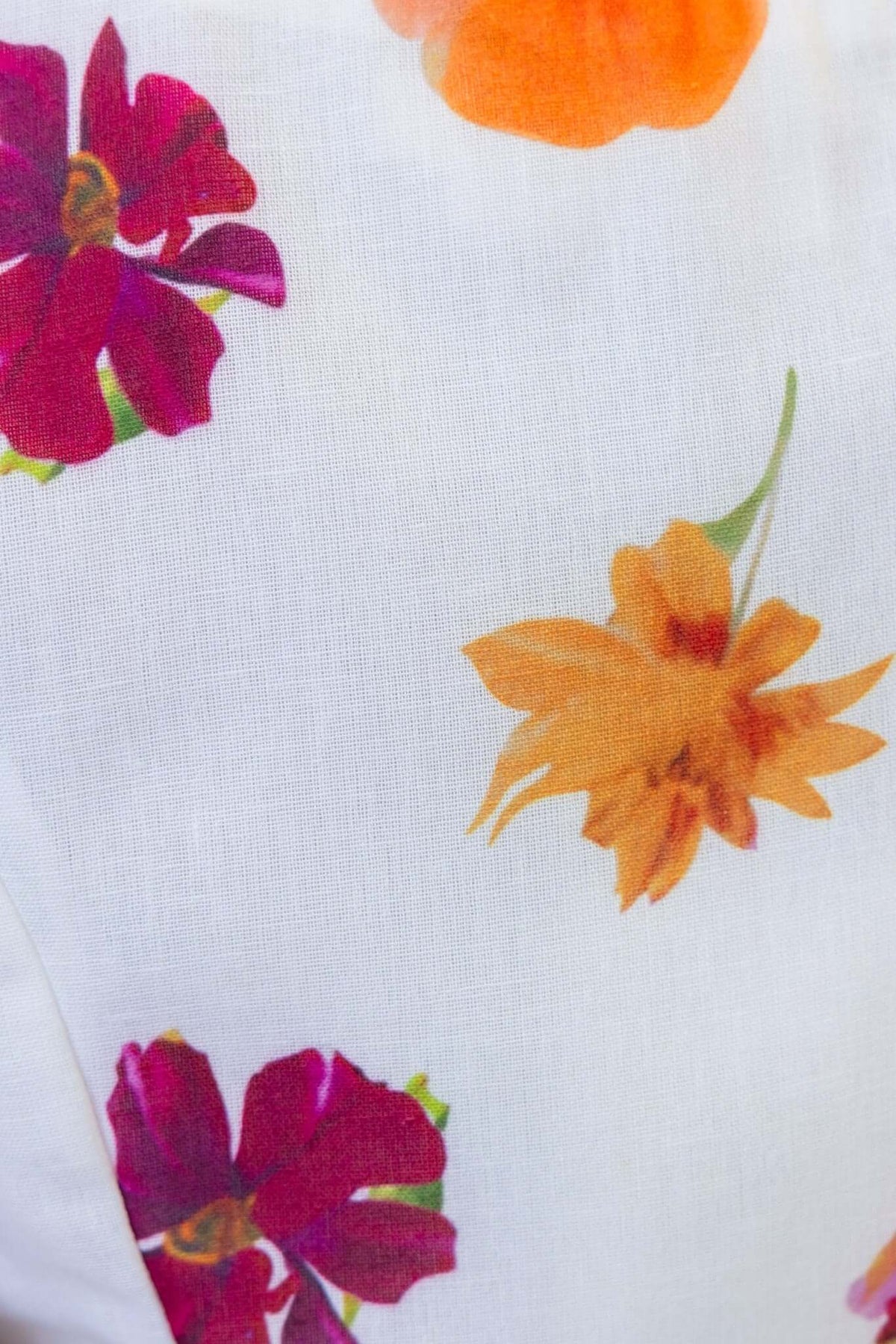 Close-up of floral fabric featuring vibrant pink and orange flowers on a white background.