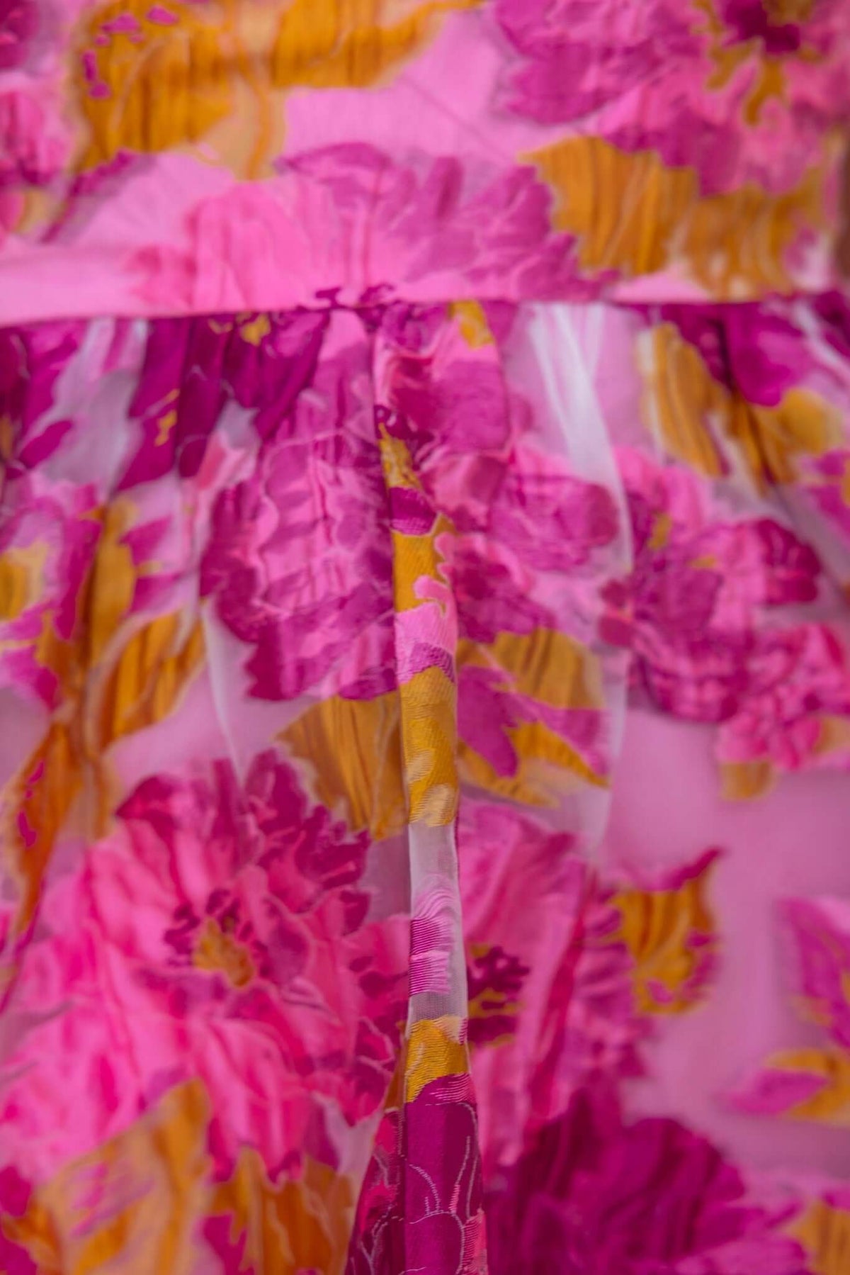 Close-up of the Wander More Dress showcasing the vibrant pink and yellow floral fabric with layered design.