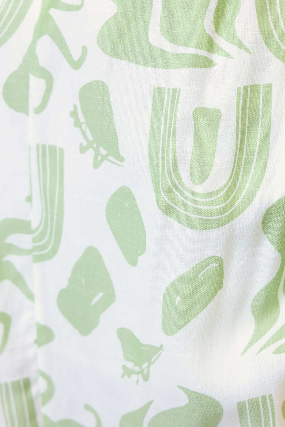 Derry Maxi Dress fabric close-up featuring playful green abstract patterns on a light background.