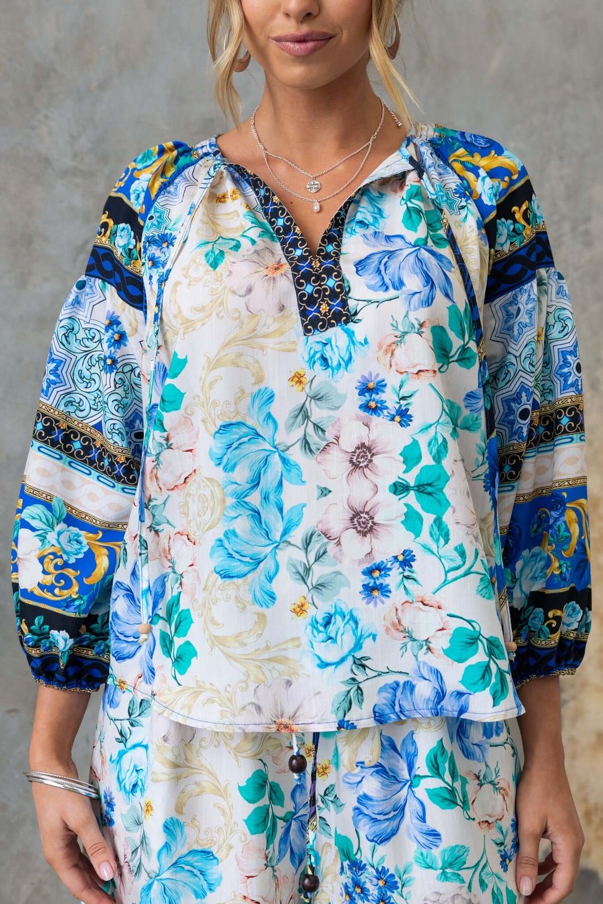 Floral print Valora Top with V-neckline, tie detail, and elastic sleeves in bright colors.