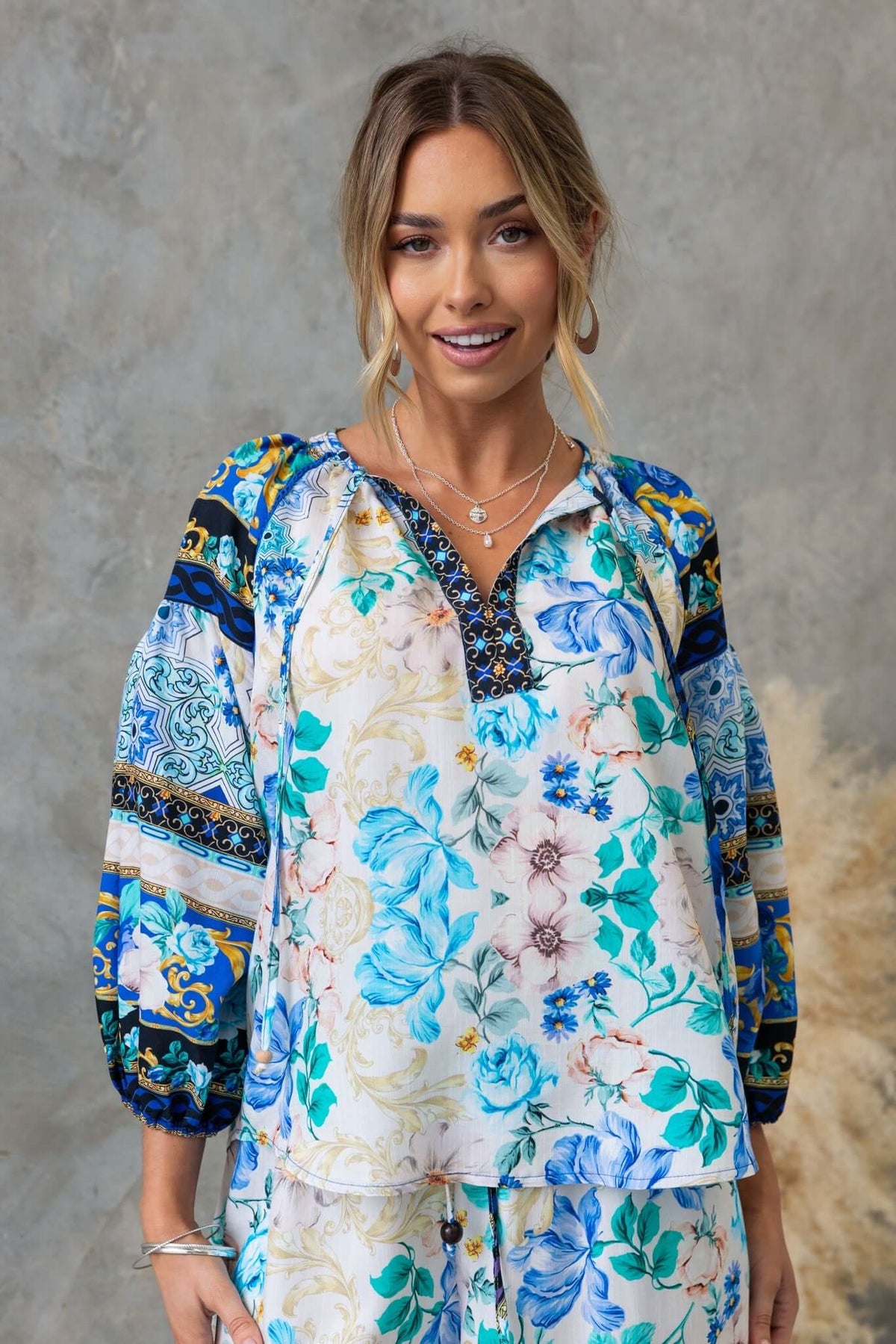 Valora Top featuring a floral print with a V-neckline and tie detail, styled with elastic sleeves.