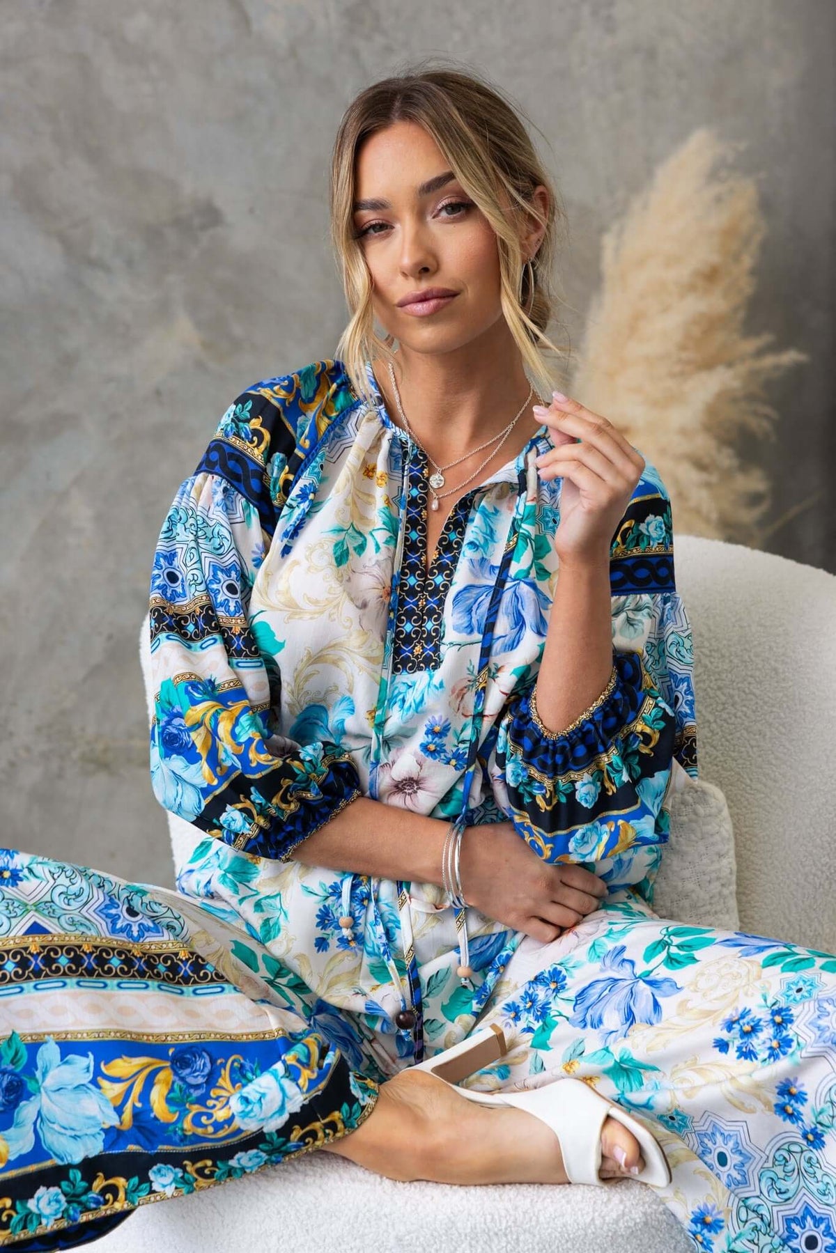 Woman wearing Valora Top, featuring blue floral print and V-neckline, captured in a stylish indoor setting.