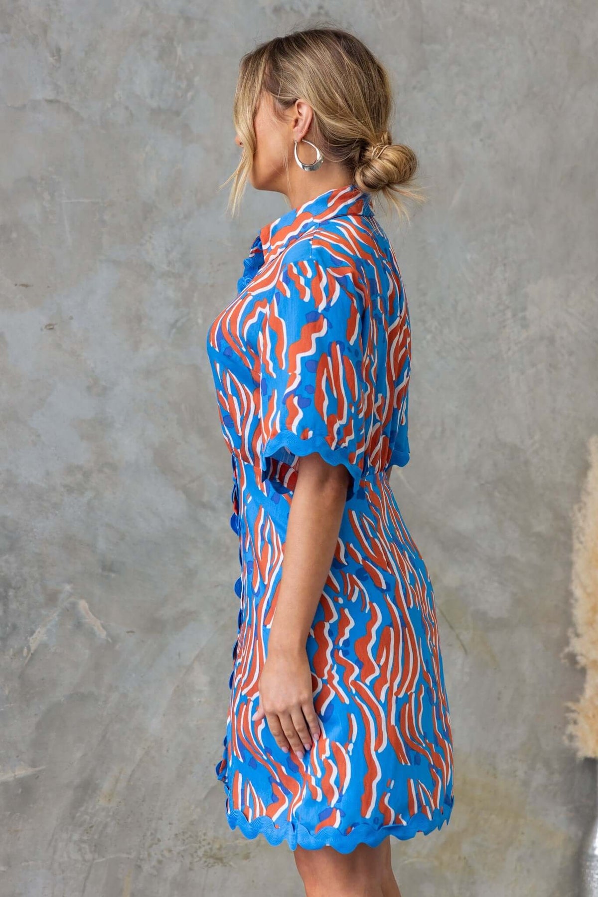 Side view of Alfonzo Dress featuring a colorful pattern, button-up front, and removable belt. Made from 100% Rayon.