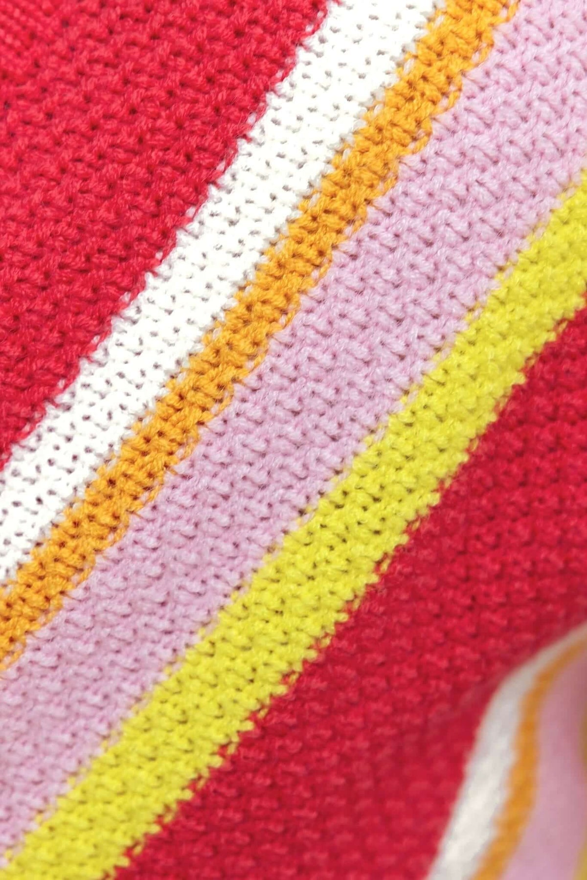 Close-up of textured knit fabric featuring vibrant red, pink, yellow, and white stripes, ideal for stylish dress designs.
