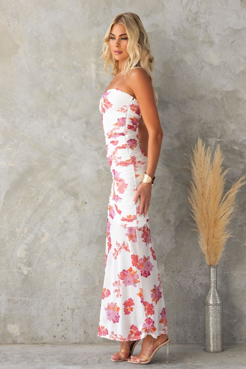 Side view of a woman in a strapless floral maxi dress with ruching and mesh overlay, perfect for summer events.