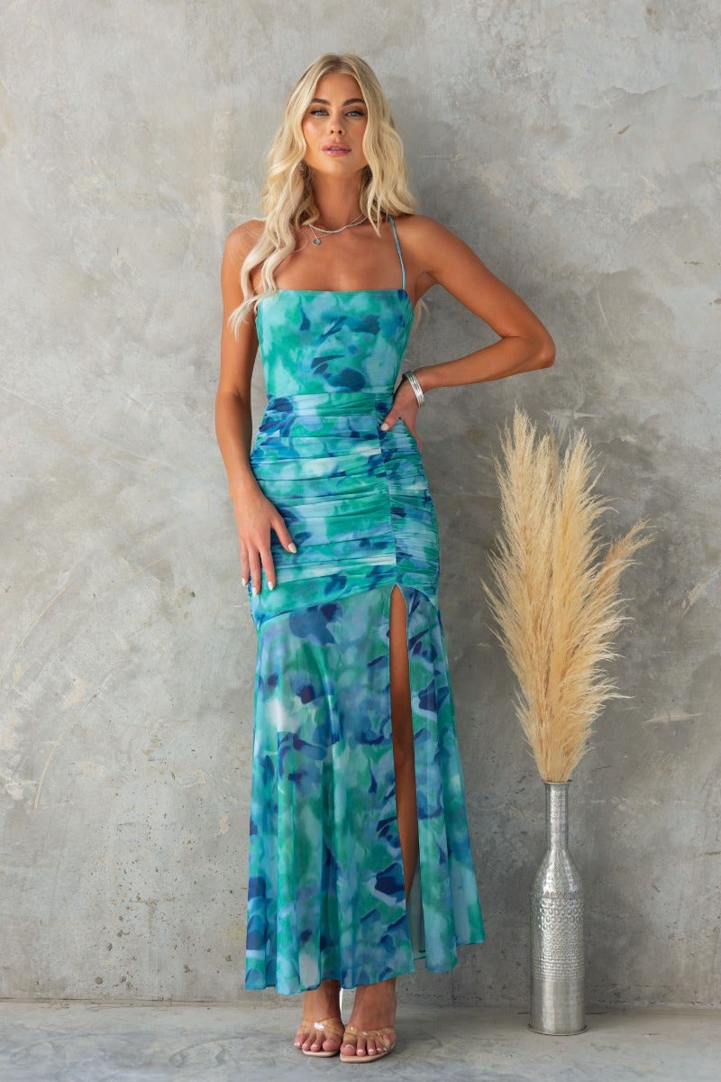 Model wearing Special Guest Maxi Dress with abstract print, adjustable straps, and front split against a textured background.