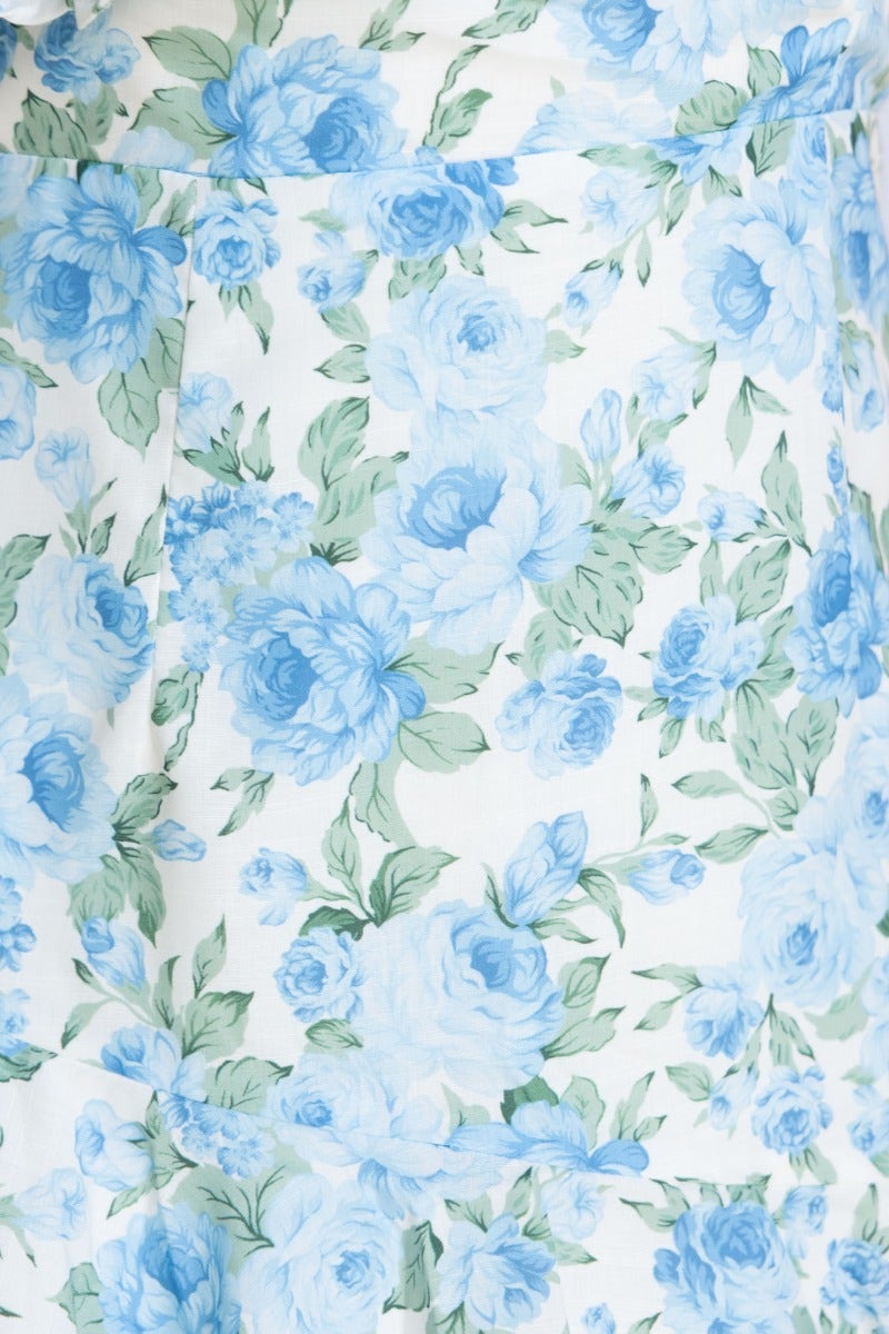 Floral print detail of Uze Dress featuring blue roses on a soft background, showcasing elegant design elements.