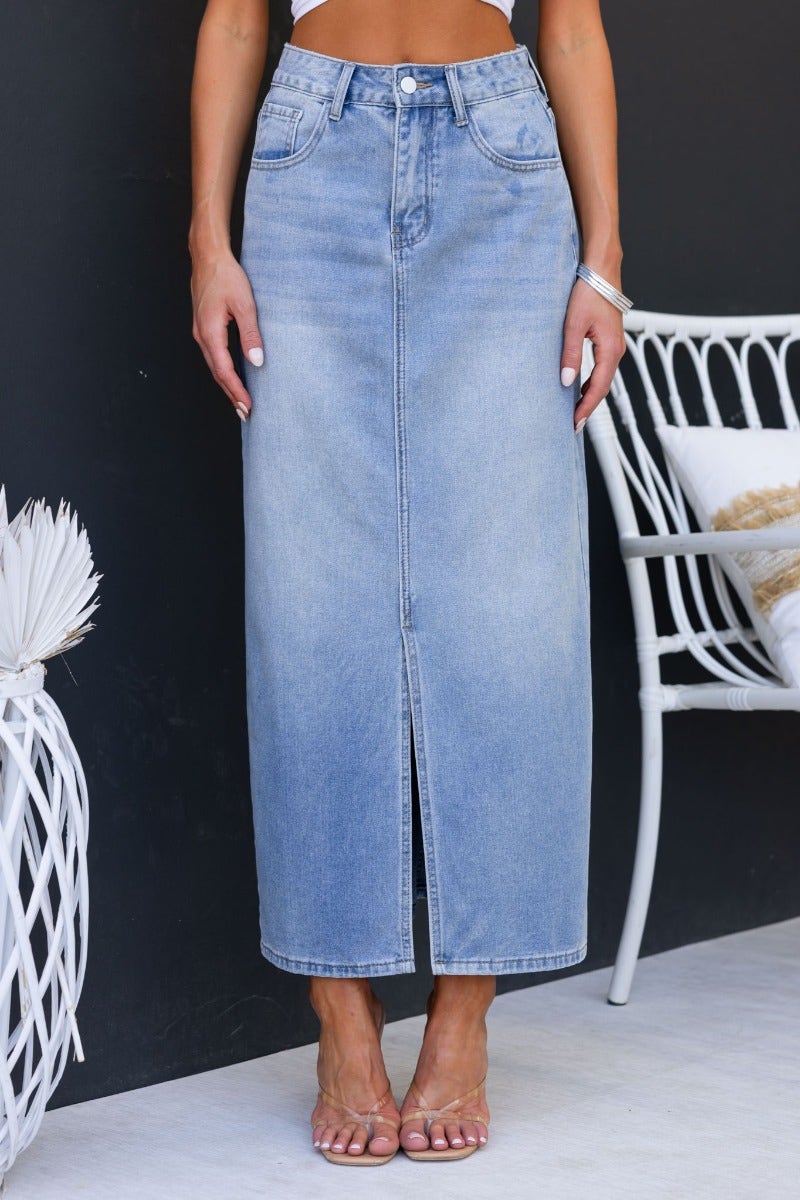 Light wash denim maxi skirt with front split and mid-high waist, styled with a trendy top and sandals.