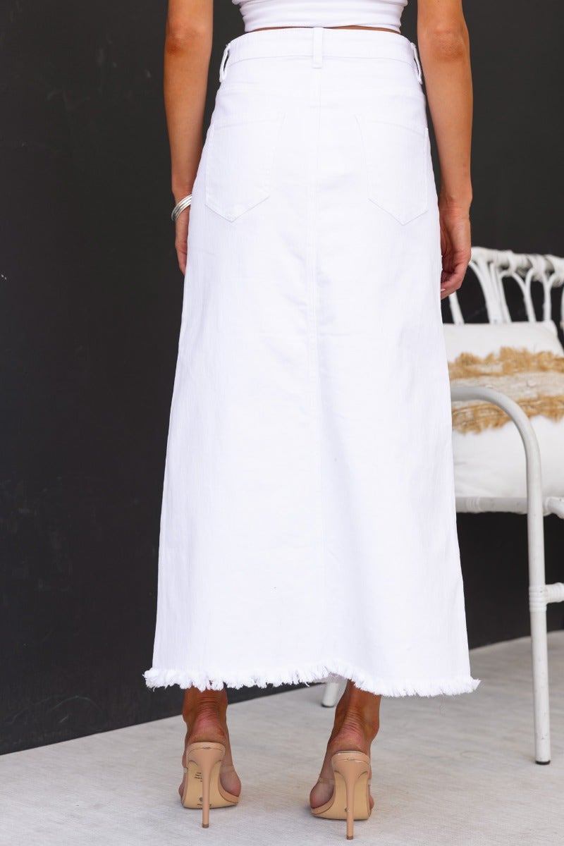 Back view of a white denim maxi skirt with frayed hemline, showcasing a mid-high waist and pockets.