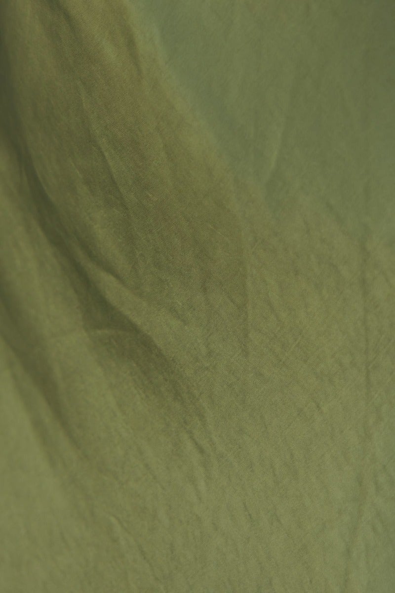 Close-up of textured green fabric, perfect for a forest maxi dress with a satin look and feel.