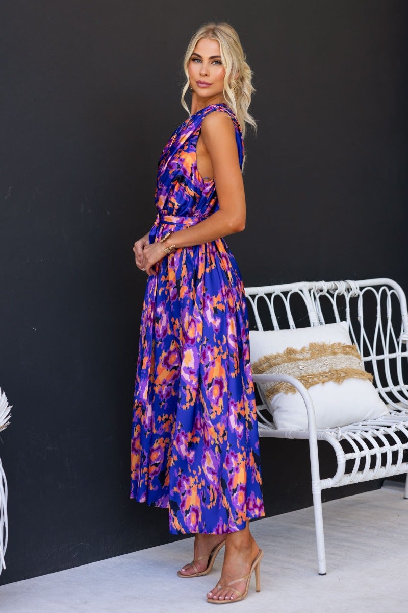 Model wearing multi-colour Ragie Maxi Dress featuring a one-shoulder style and elastic waistband, styled with sandals.