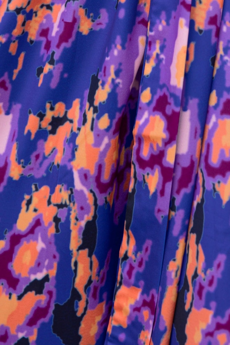 Close-up of the vibrant multi-colour fabric pattern of the Ragie Maxi Dress featuring blues, purples, oranges, and blacks.