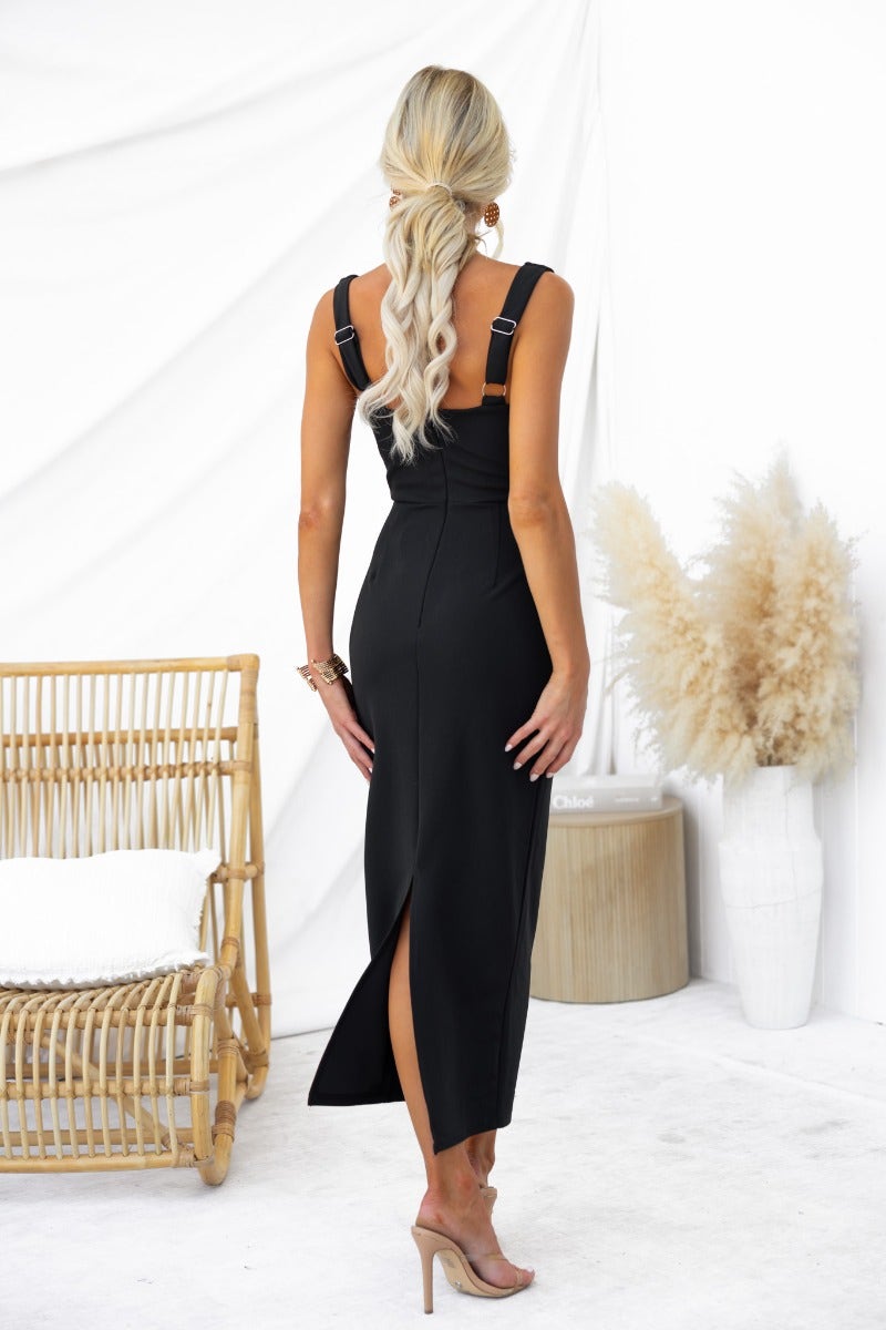 Back view of a black bodycon maxi dress with adjustable straps and split, styled with a casual braid.