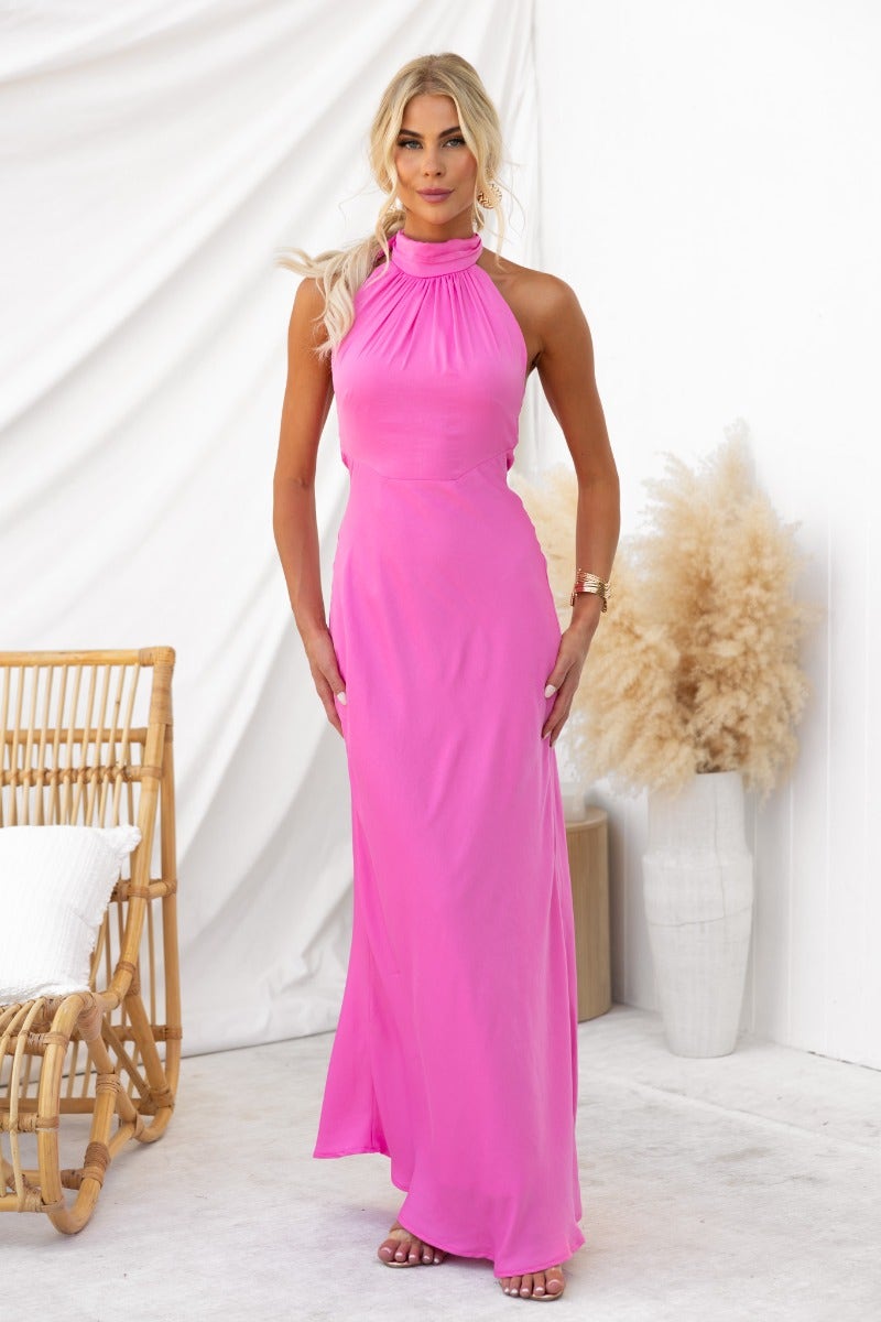 Model wearing the Forbidden Love Maxi Dress in vibrant pink, featuring a high tie neckline and sleek design.