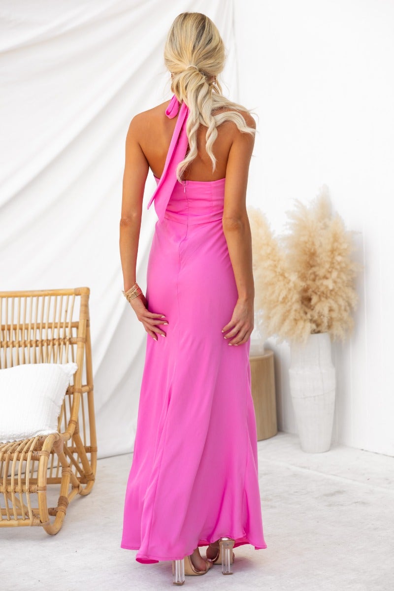 Model wearing the Forbidden Love Maxi Dress in bright pink, showing the back view with high tie neckline.