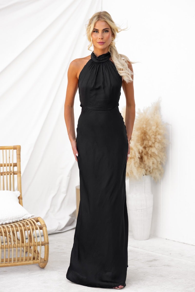 Model wearing the Forbidden Love Maxi Dress, a black halter neck gown with slight sheen and fitted silhouette.