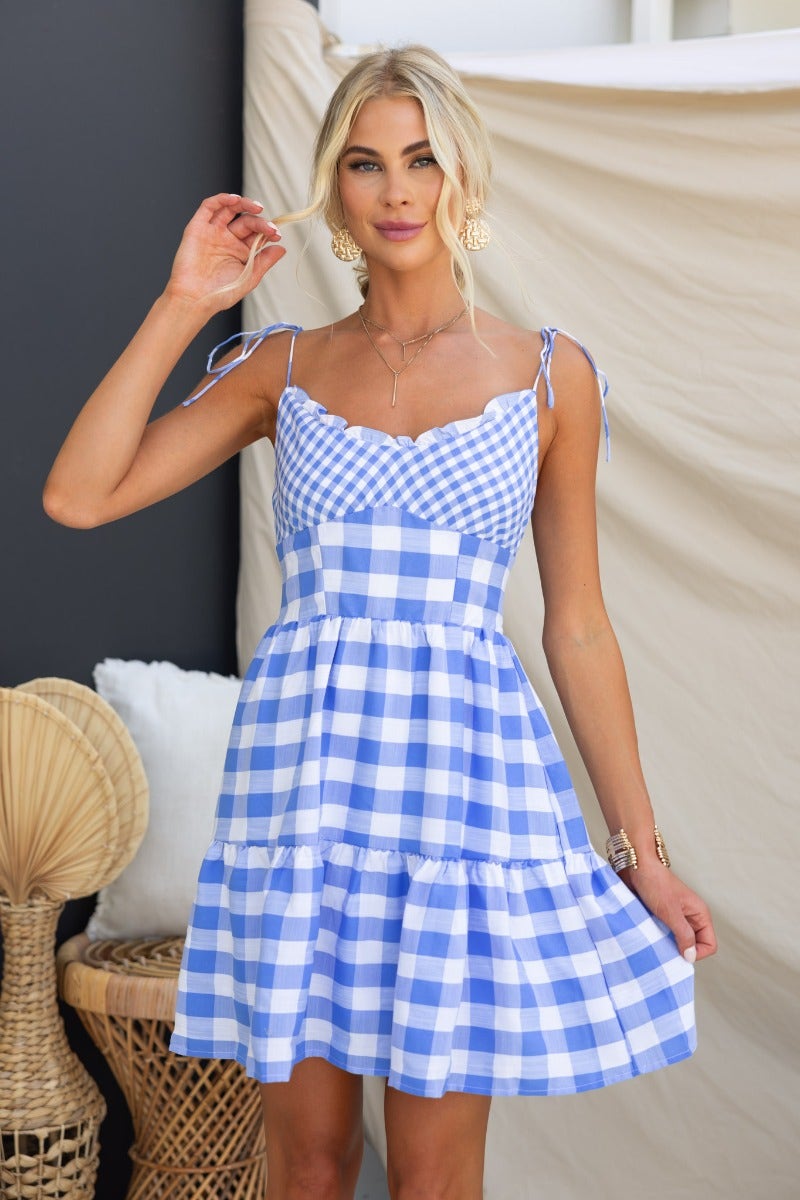 Blue and white plaid Dorothy dress with adjustable ties, featuring a tiered skirt and a lightweight cotton blend.