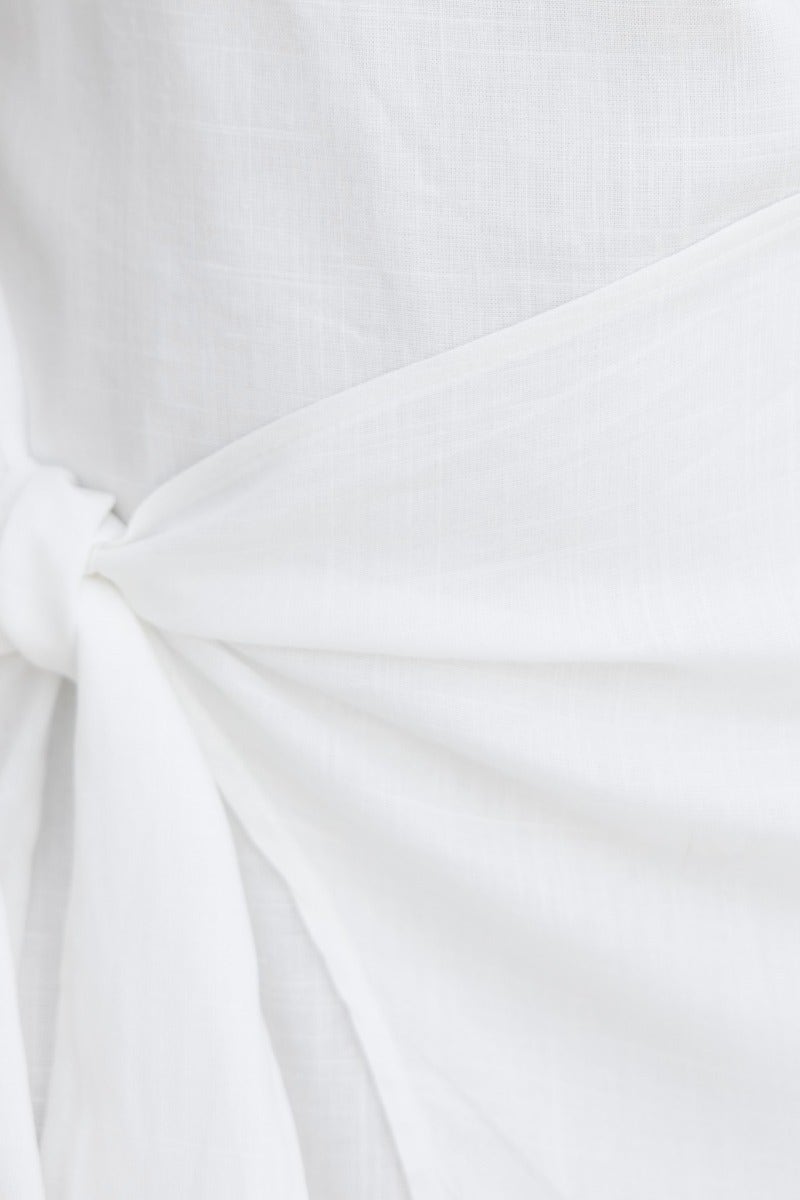 Close-up of Beloved Midi Dress featuring a tie detail and linen texture in soft white fabric.