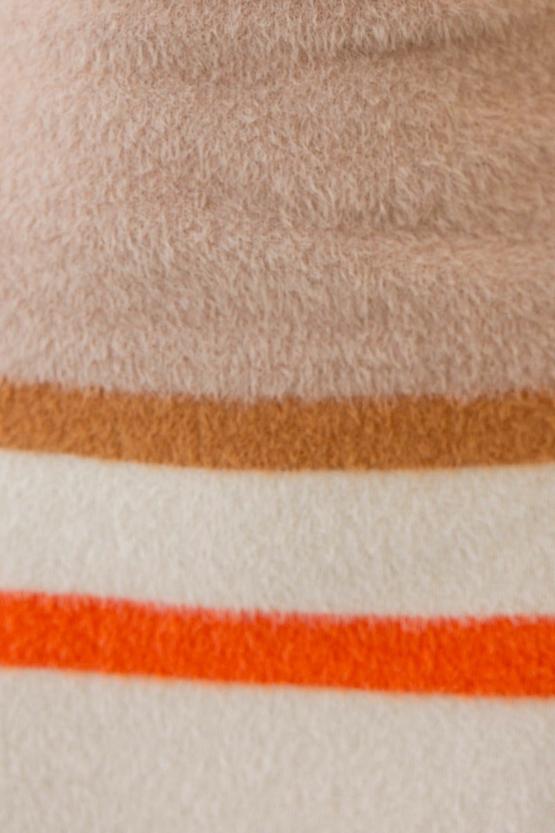 Close-up of soft fluffy knit fabric in warm tones featuring beige, brown, and orange stripes.