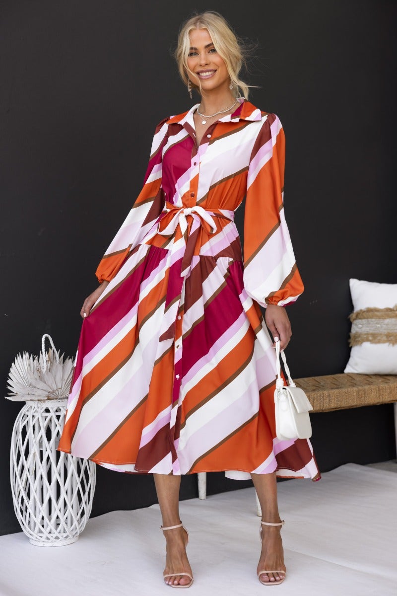 Model wearing the Nylah Midi Dress, a multi-colour striped dress with a collar, button-up front, and removable belt.