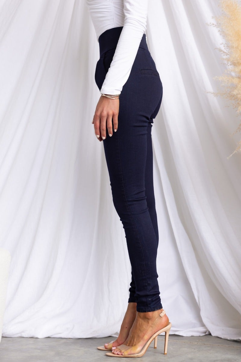 Side view of navy high-waisted pants with a tight fit, styled with a fitted white top and heels.