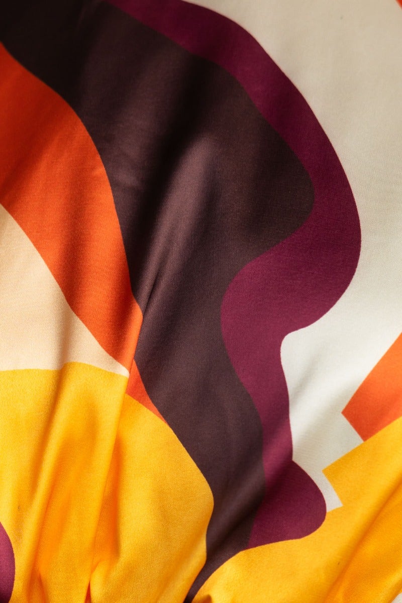 Close-up of colorful fabric with orange, yellow, and purple patterns, perfect for a stylish maxi dress.