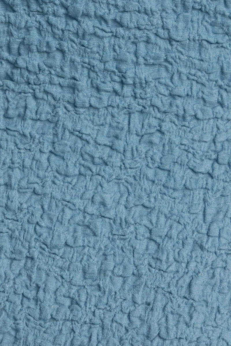 Textured blue fabric close-up, showcasing crinkled surface for a stylish and comfortable midi dress.