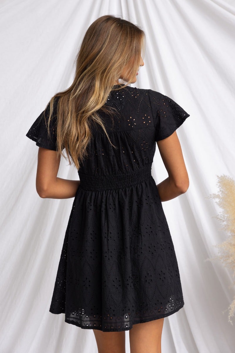 Back view of the black Anglaise Udela Dress featuring a smocked waist and flutter sleeves.