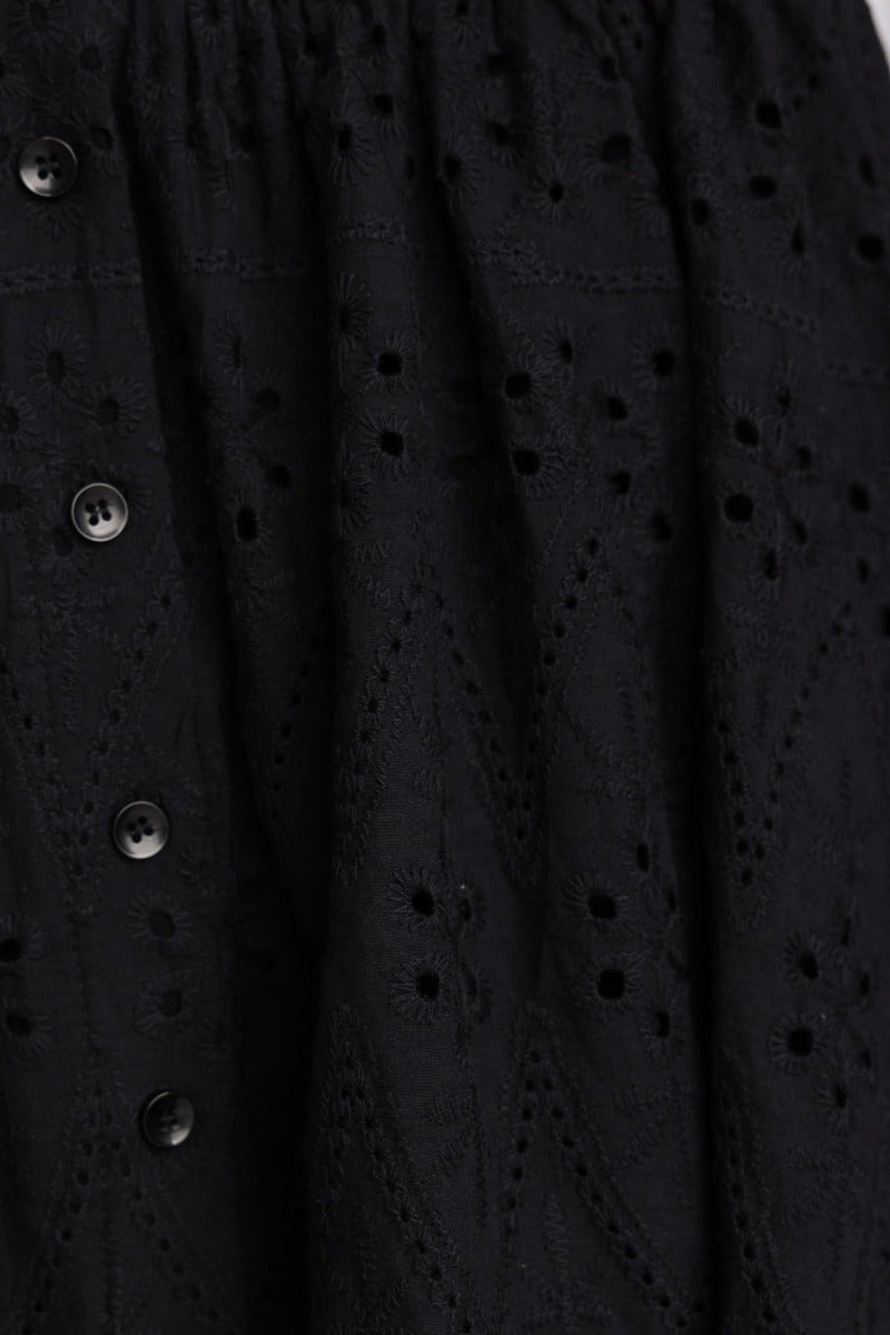 Close-up of black Anglaise dress fabric featuring V-neckline and button-up front detail.