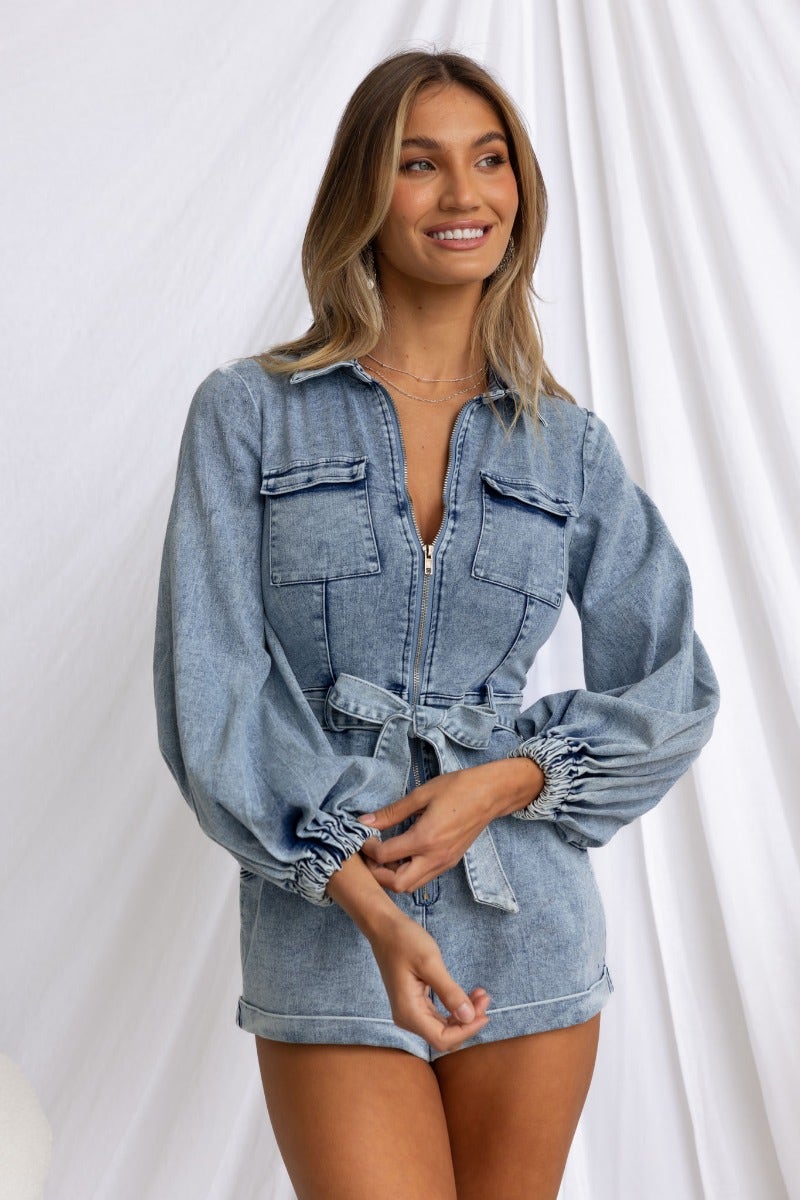 Model wearing Rover Denim Playsuit with zip-up front, pockets, and removable belt, showcasing slight stretch and relaxed fit.