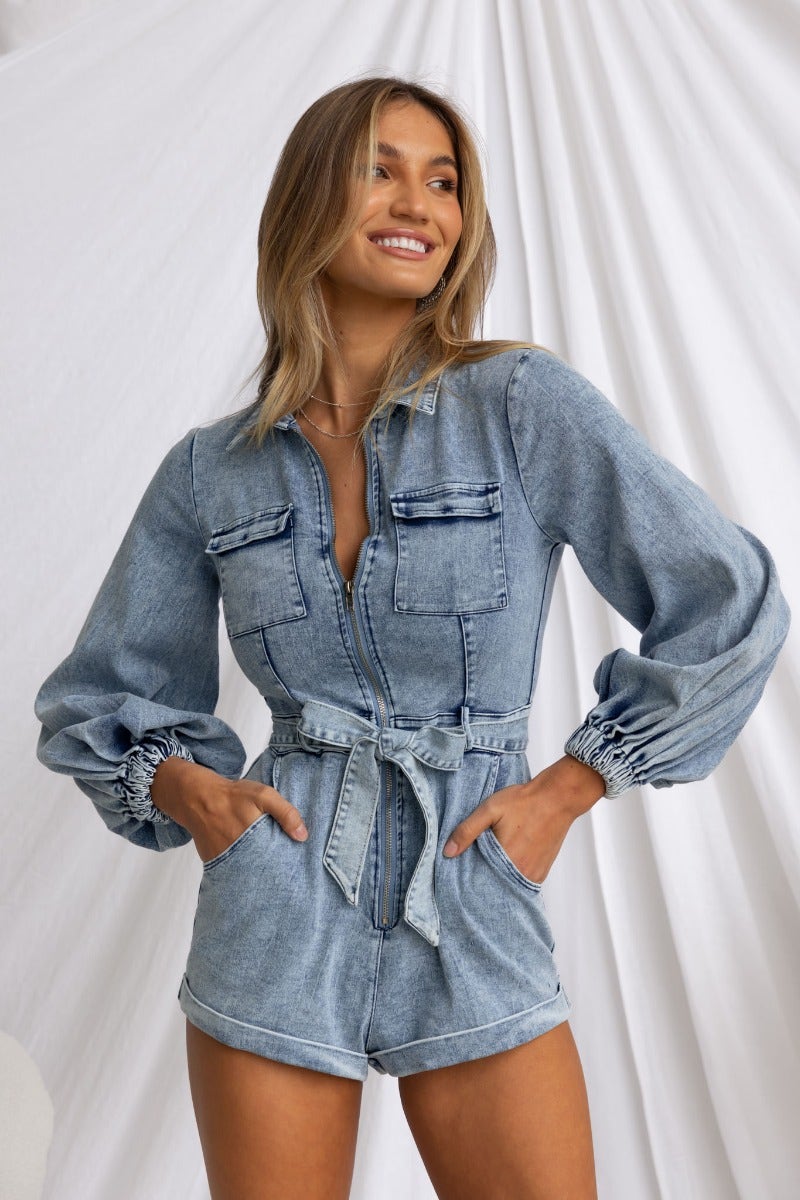 Model wearing Rover Denim Playsuit with zip-up front, elastic cuffs, and pockets, showcasing a relaxed fit in light denim.